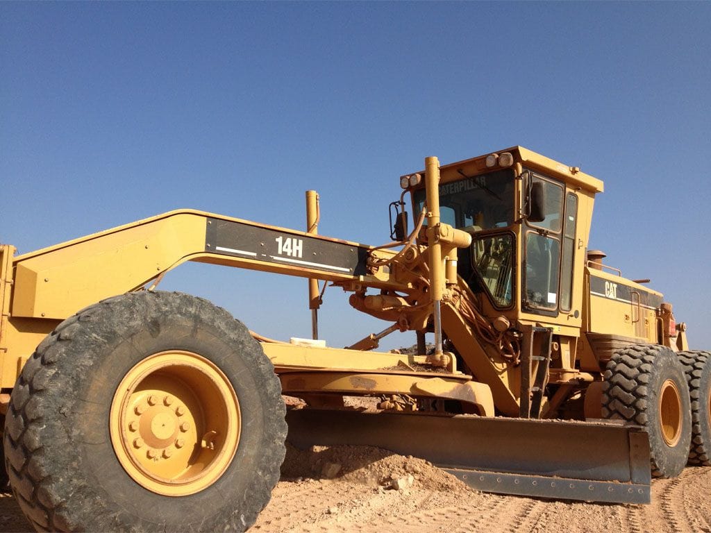 Cat 14H motor grader, close three-quarter view on a gravel pad