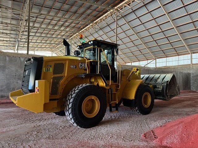 Cat 962M wheel loader inside a large shed with a red mineral floor