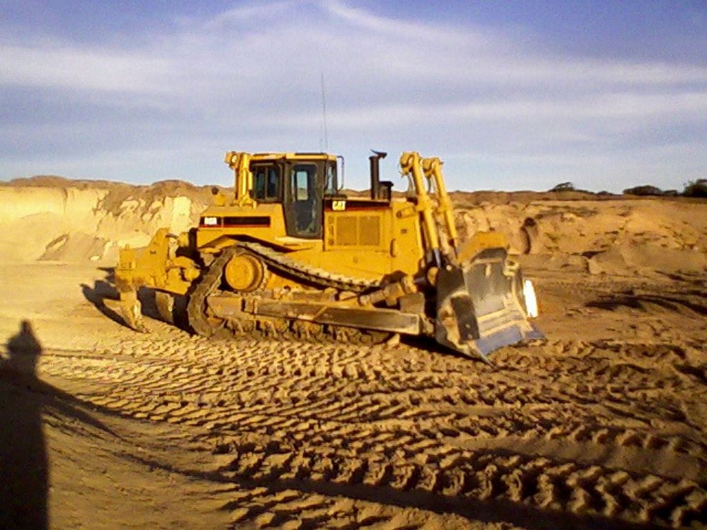 Cat D8 dozer pushing sand on a dune site in warm light