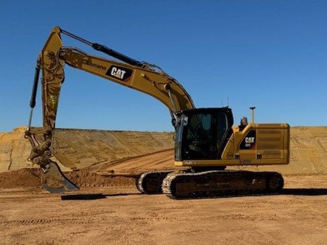 Cat next generation excavator with Lenane decals on a red dirt bench under a blue sky