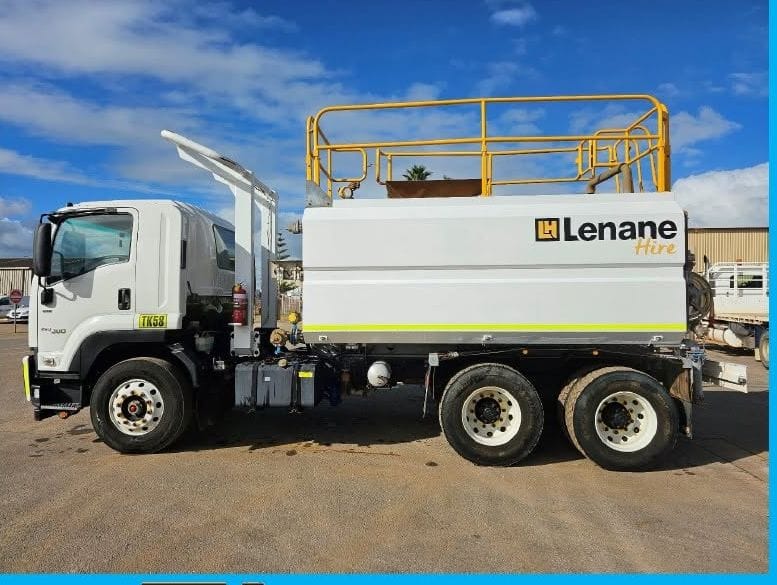 White Isuzu 6x4 water cart with a Lenane Hire tank and yellow handrails, side on in the yard
