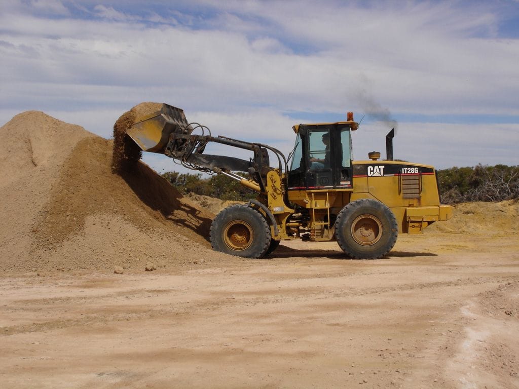 Cat integrated tool carrier loader with its bucket raised at a sand stockpile