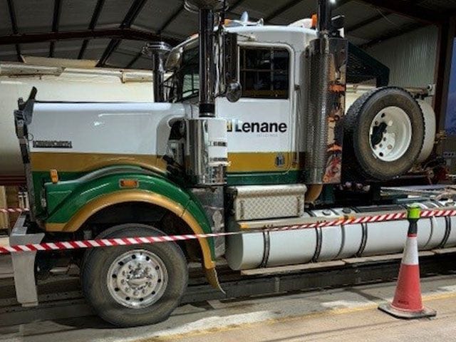 White and green Kenworth prime mover with the Lenane door logo inside the workshop