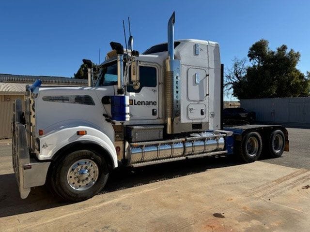 White Kenworth T909 prime mover with Lenane logo, side view in the yard